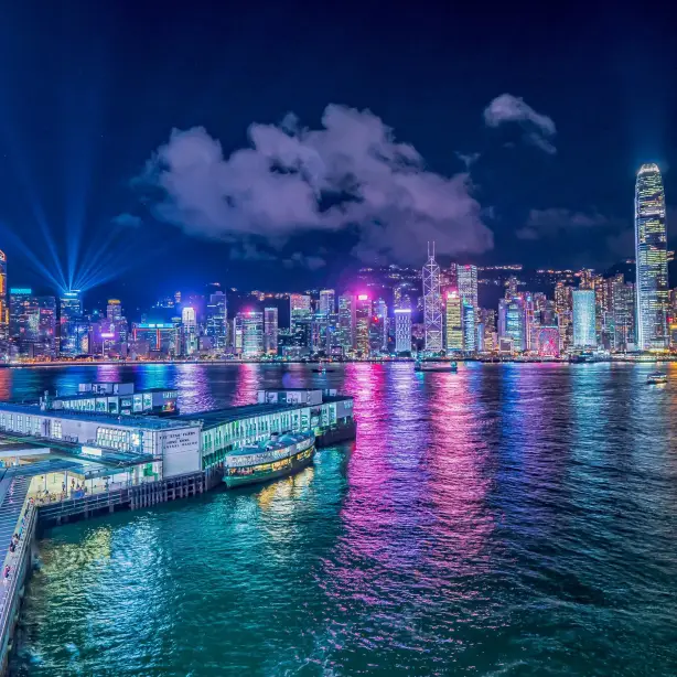 View of the city brightly lit up at night, colours reflecting in water in Hong-Kong