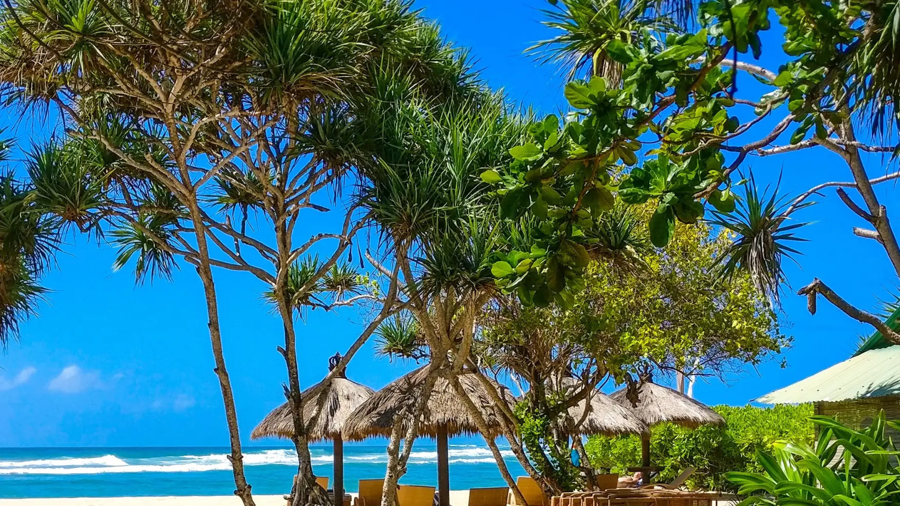 Strand mit Strohhütten und Sitzgelegenheiten mit Blick auf den Ozean in Bali