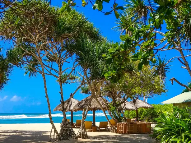 Beach with straw huts and seating areas looking out at the ocean in Bali