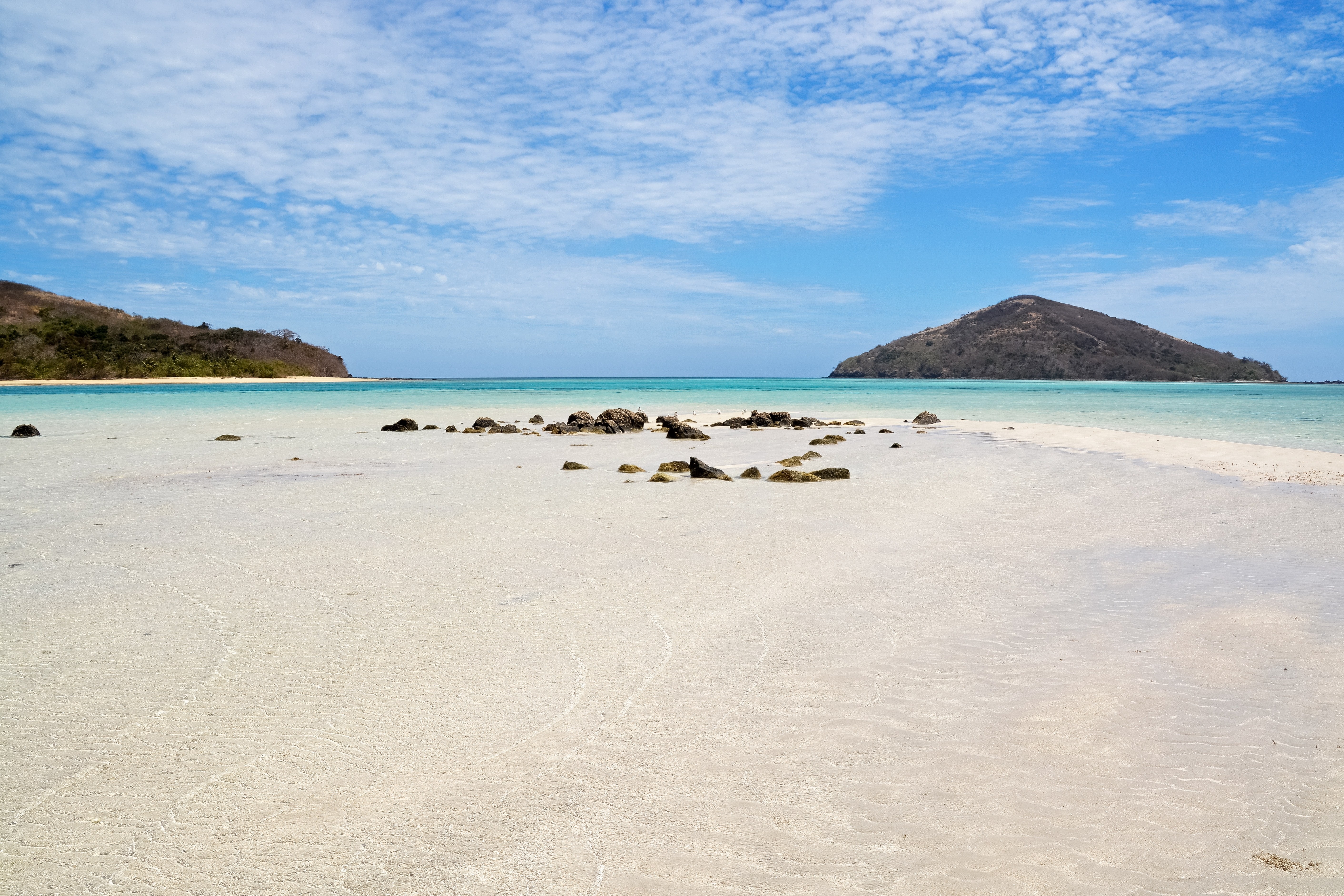 rocks on the sand of Fiji beach with islands in the background