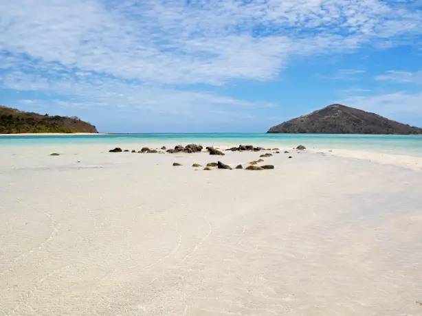 rocks on the sand of Fiji beach with islands in the background