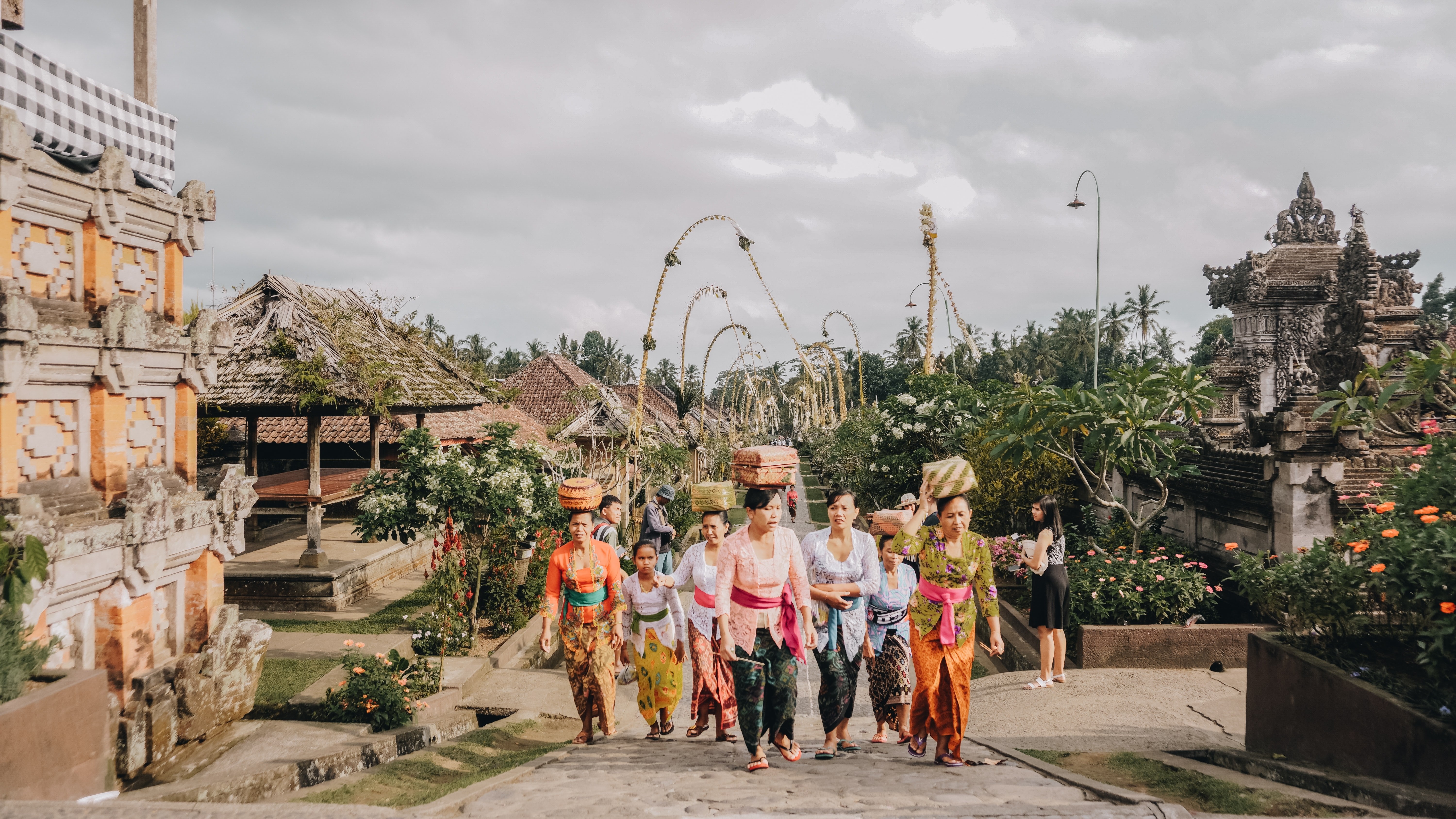 Frauen mit Körben auf Kopf laufen durch Tempelstraße in Bali
