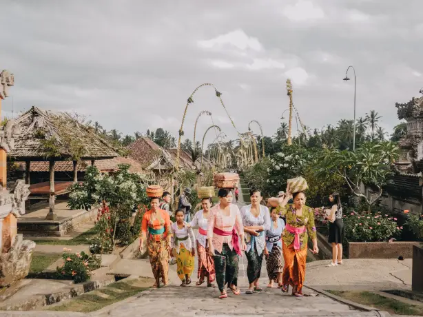 Frauen mit Körben auf Kopf laufen durch Tempelstraße in Bali