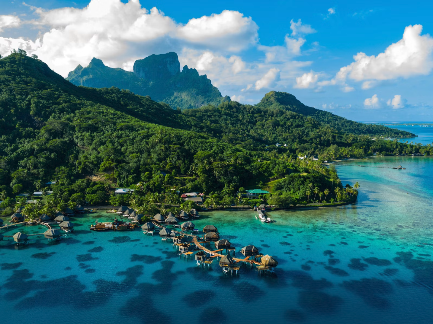 Überwasserunterkünfte mit Blick auf das Meer und die Berge im Hintergrund