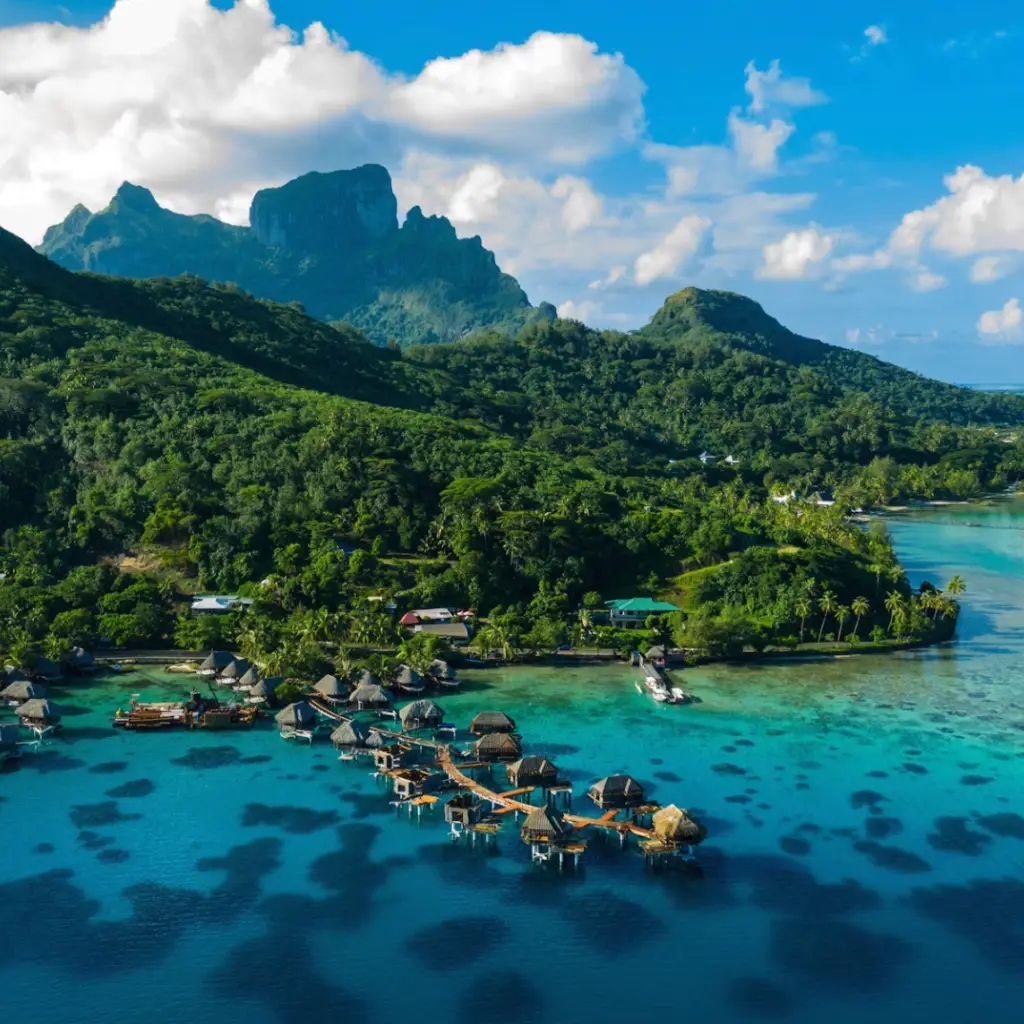 Überwasserunterkünfte mit Blick auf das Meer und die Berge im Hintergrund