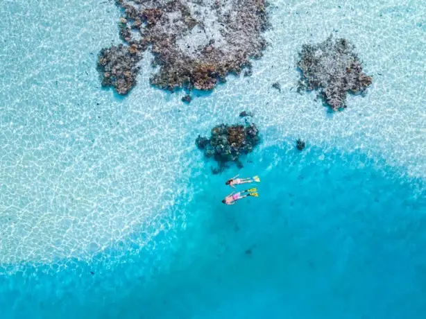 Aerial view of a couple snorkelling in the bays of Cook Islands