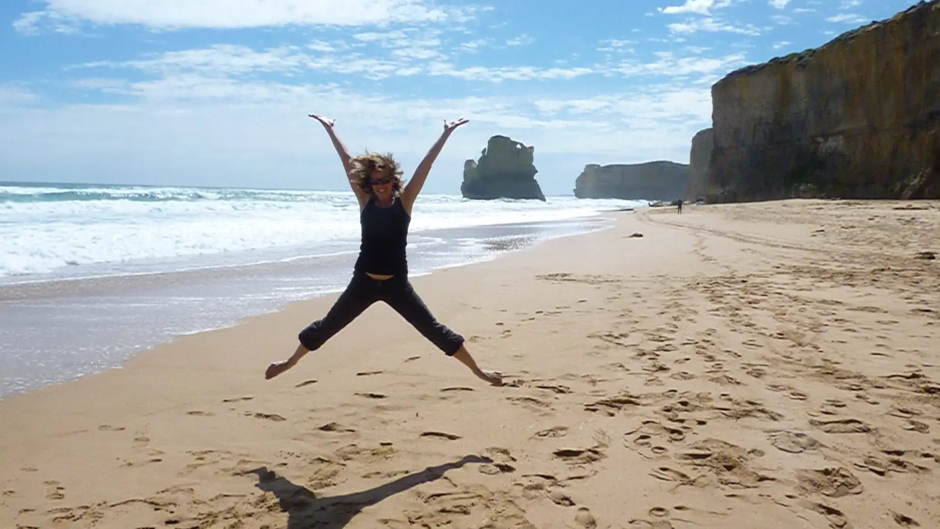 Frau springt an Strand von Australien