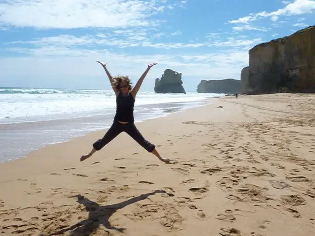 Frau springt an Strand von Australien