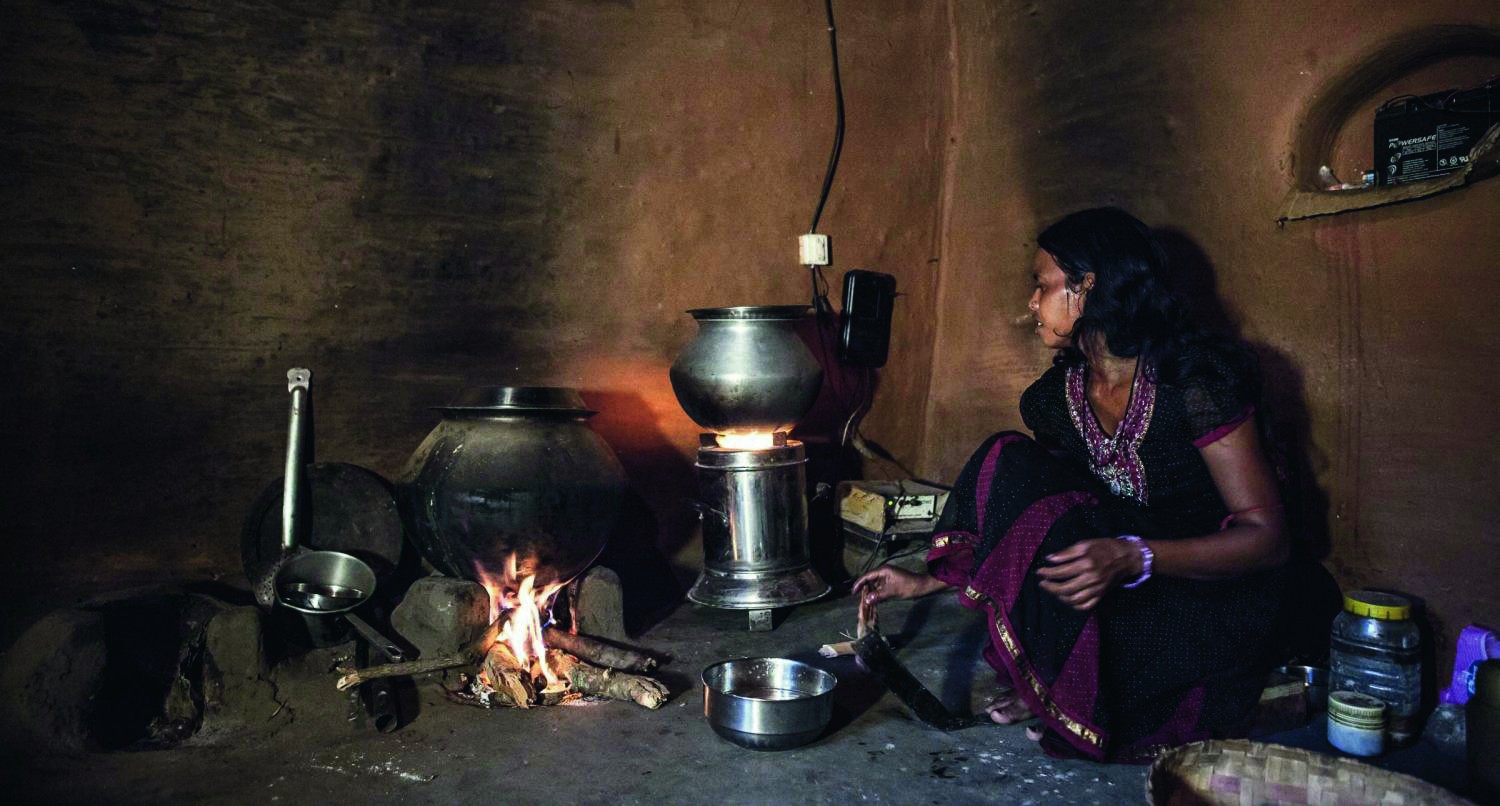 Nachhaltige Essenszubereitung in Indien, Frau sitzt an Ofen