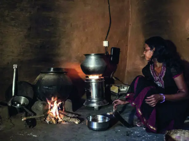 Nachhaltige Essenszubereitung in Indien, Frau sitzt an Ofen