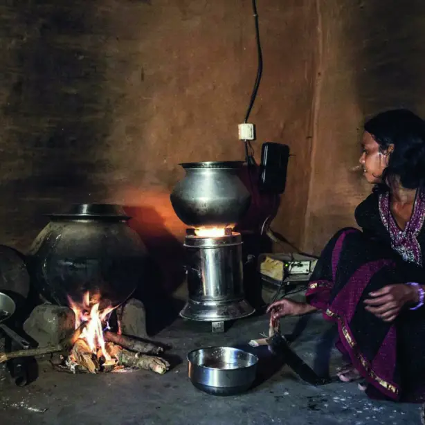 Nachhaltige Essenszubereitung in Indien, Frau sitzt an Ofen