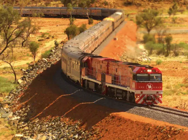 The famous Australian Ghan train travels through a red rock landscape
