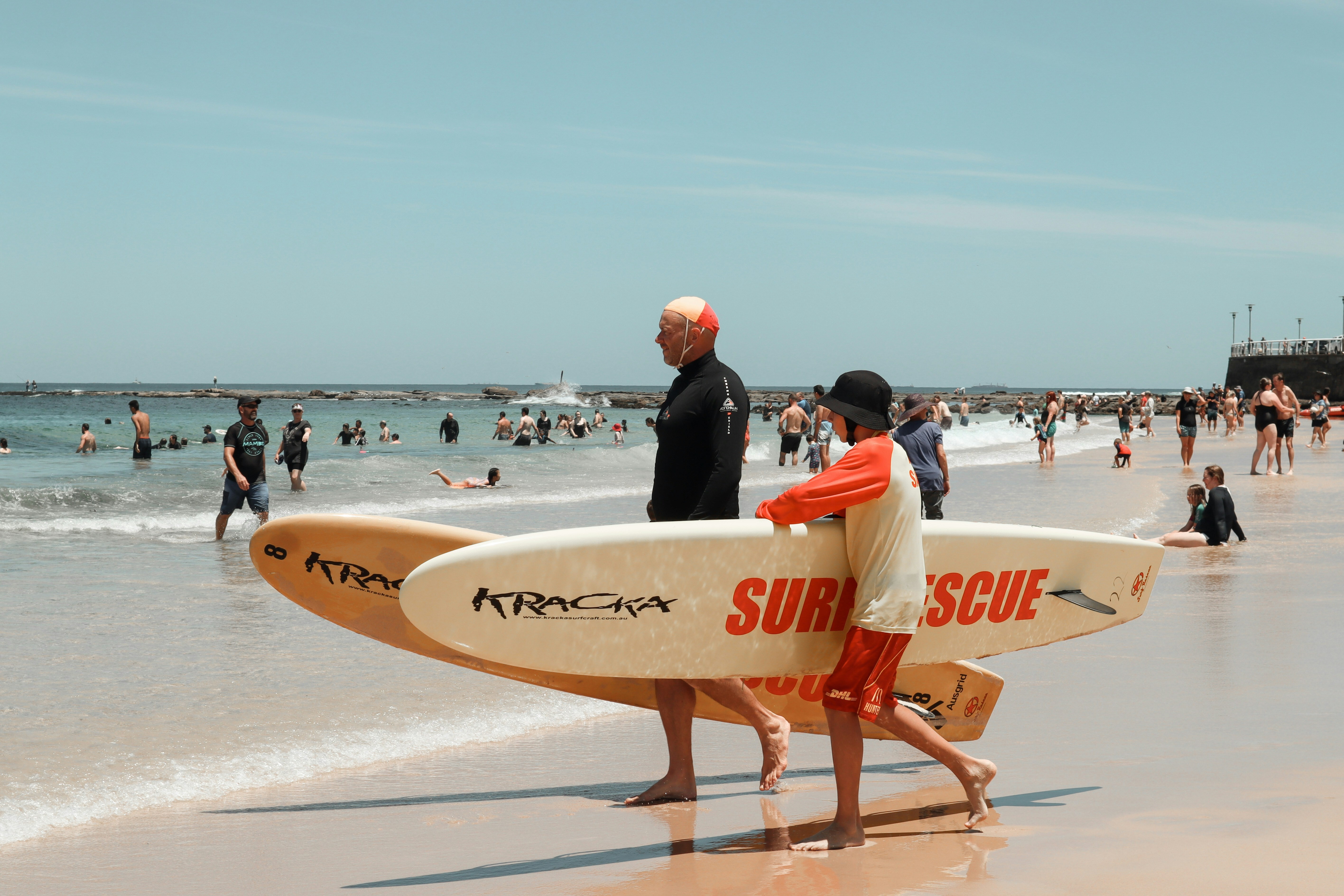 AU NSW Newcastle surfers lopen op het strand