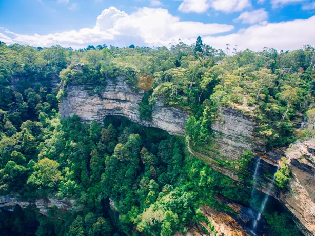 Felswand mit Bäumen und Wasserfall in Australien