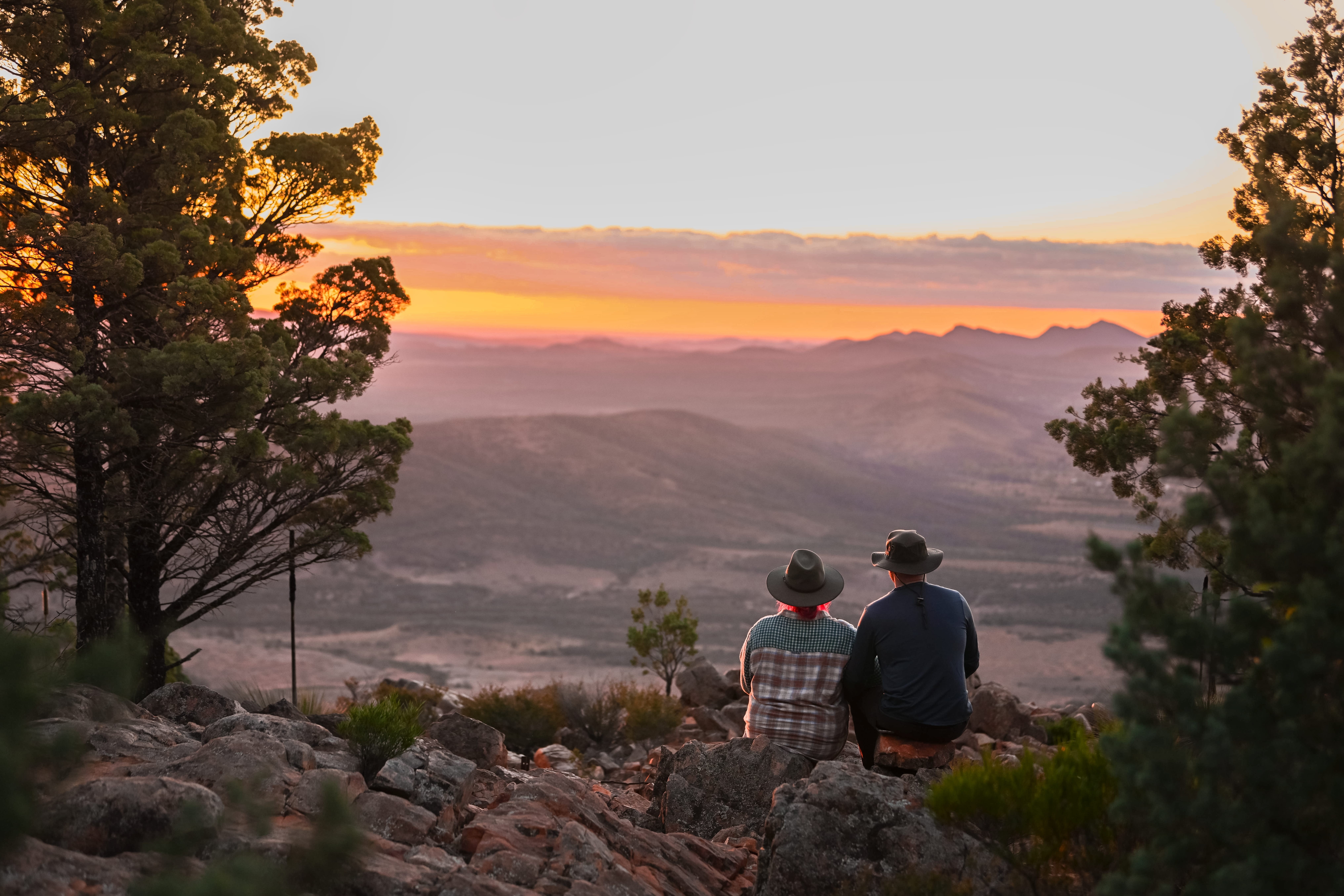 Een koppel samen zittend uitkijkend over de bergen tijdens de zonsondergang in Flinders Ranges Outback, Australië
