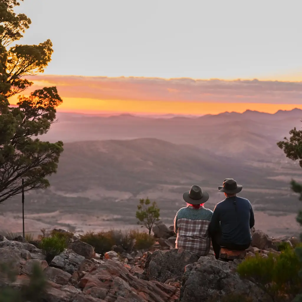 Een koppel samen zittend uitkijkend over de bergen tijdens de zonsondergang in Flinders Ranges Outback, Australië