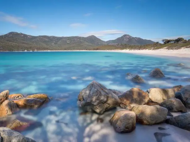Eine Landschaftsansicht der Wineglass Bay in Tasmanien mit blauem Meer und felsigen Küsten
