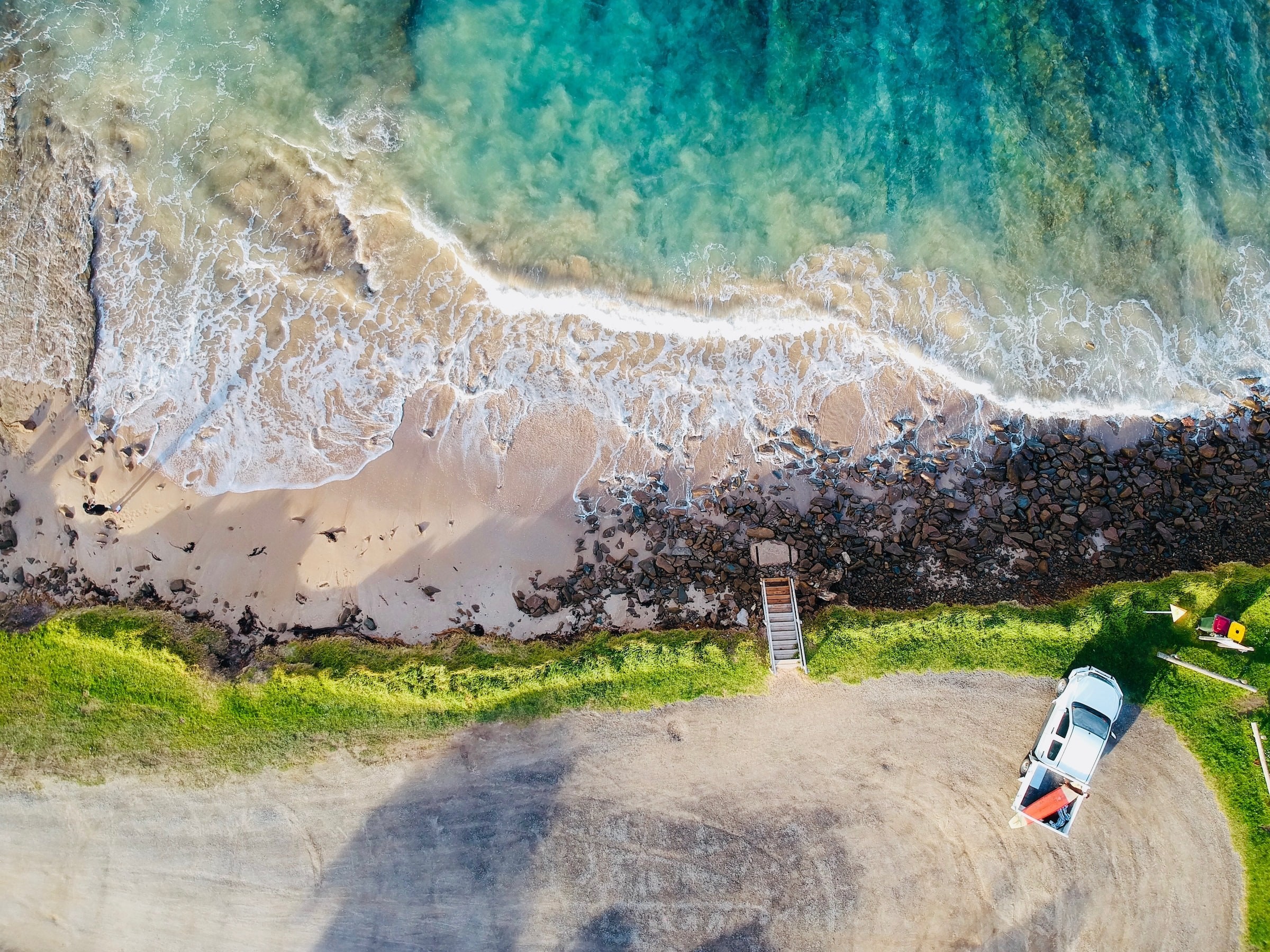 An aerial view of a car parked close to the beach at the Great Ocean Road in Australia