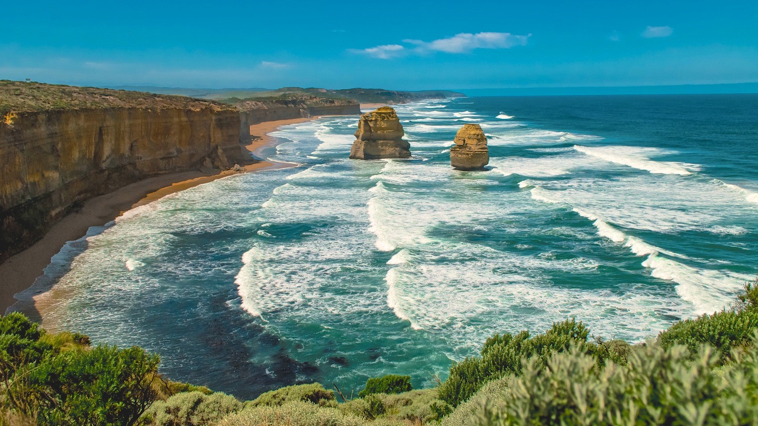 Eine zerklüftete Küstenlinie mit blauen Wellen und goldenen Felsen, Teil der Great Ocean Road in Victoria