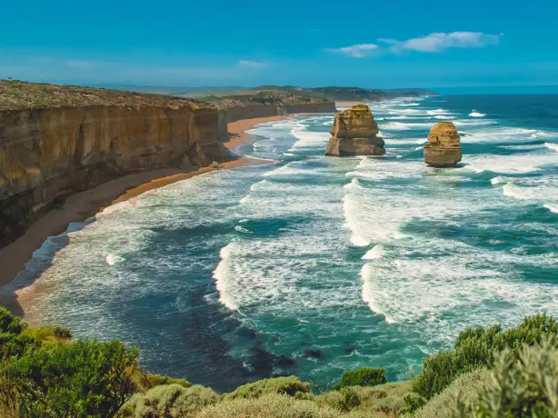 Eine zerklüftete Küstenlinie mit blauen Wellen und goldenen Felsen, Teil der Great Ocean Road in Victoria