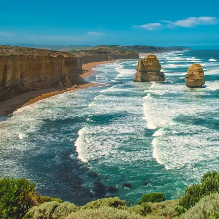 A rugged coastline with blue waves and golden rocks, part of Victoria's Great Ocean Road