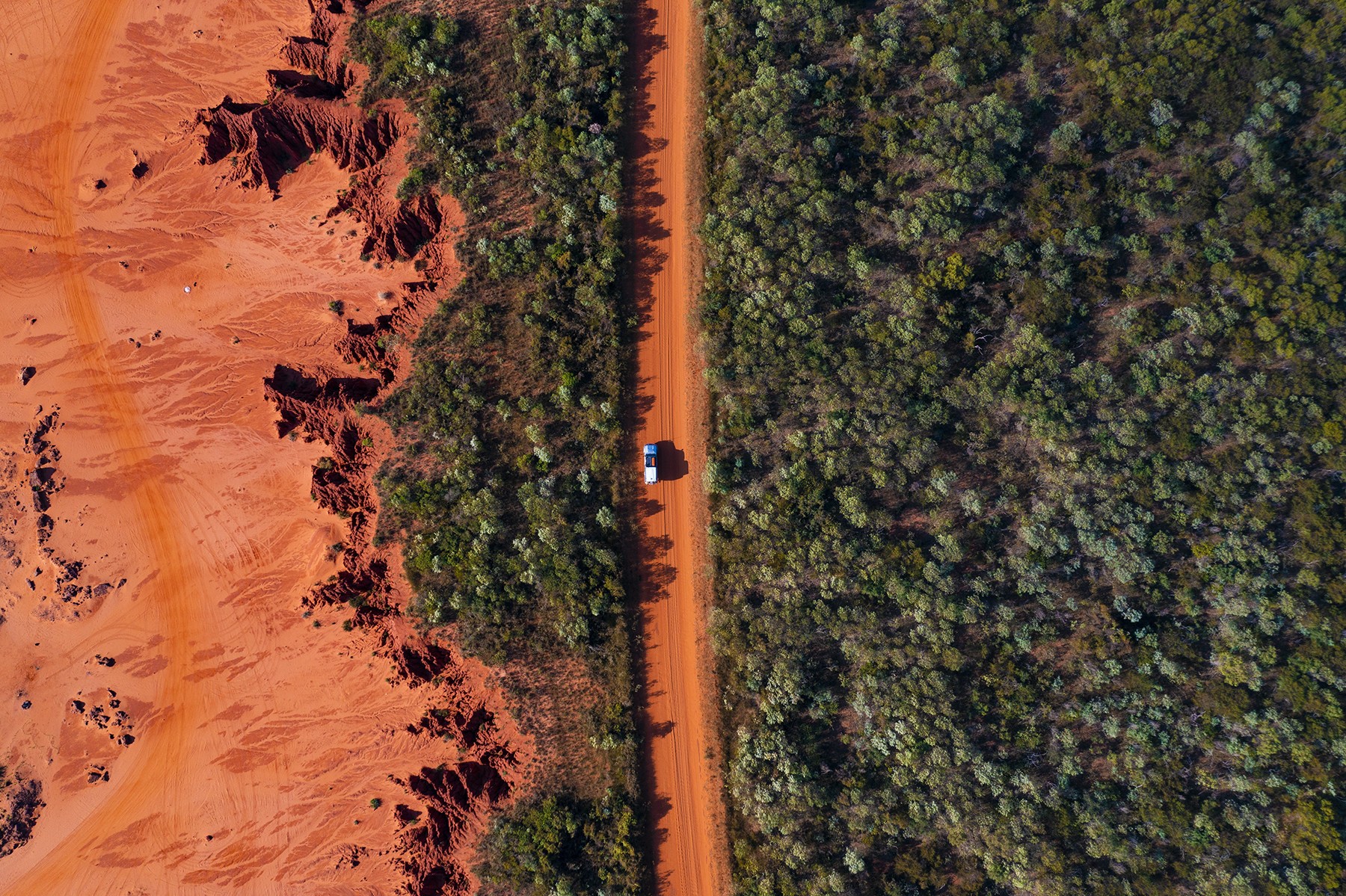 Ein Auto fährt auf einer roten Schotterstraße in Broome, Westaustralien