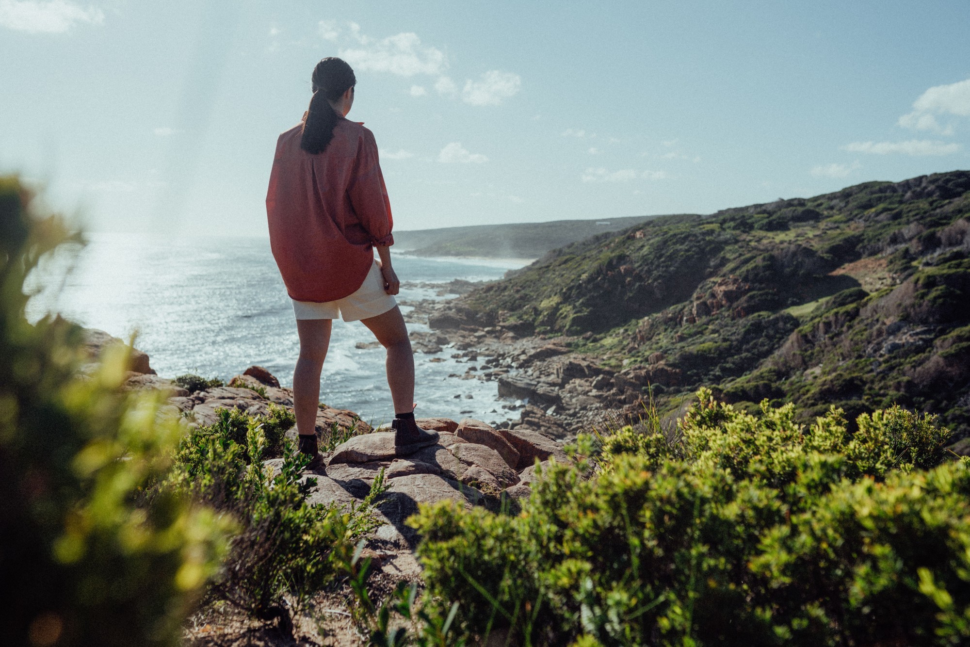 Frau steht auf Felsen und blickt über Bucht in Australieh