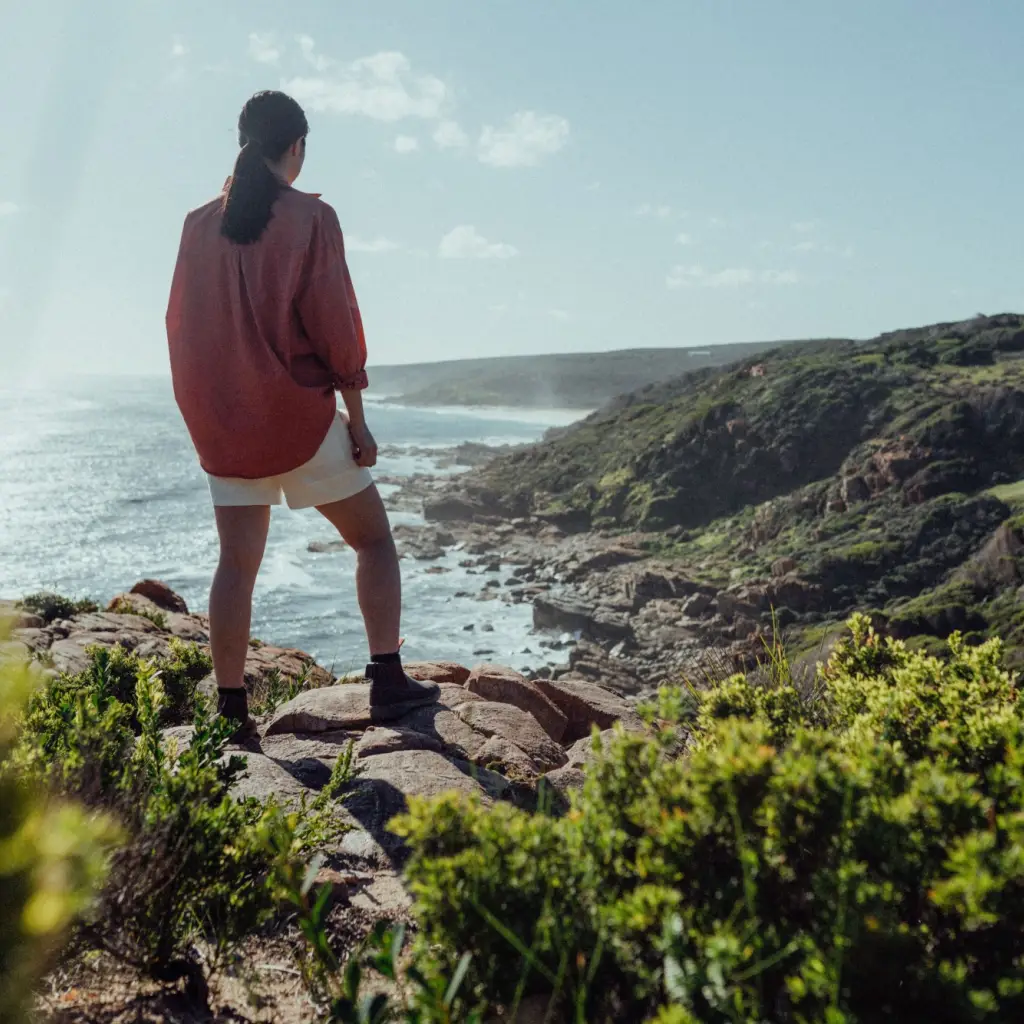 Frau steht auf Felsen und blickt über Bucht in Australieh