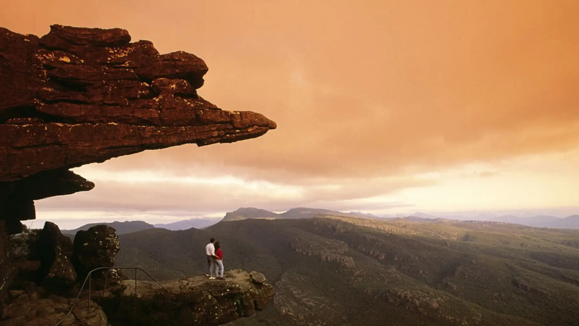 A couple standing on a rock, looking in the distance, in the Grampians National Park in Australia