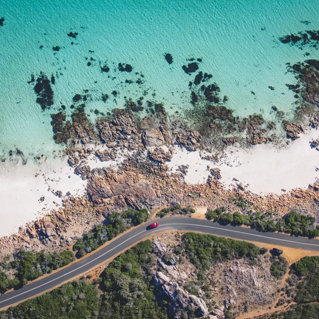 Een auto rijdt langs de kust bij Eagle Bay, West-Australië