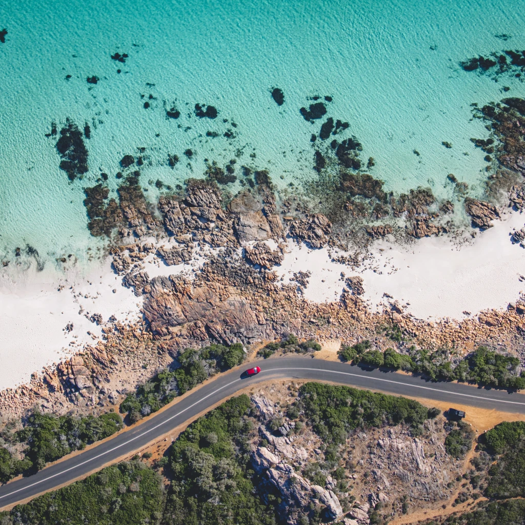 Een auto rijdt langs de kust bij Eagle Bay, West-Australië