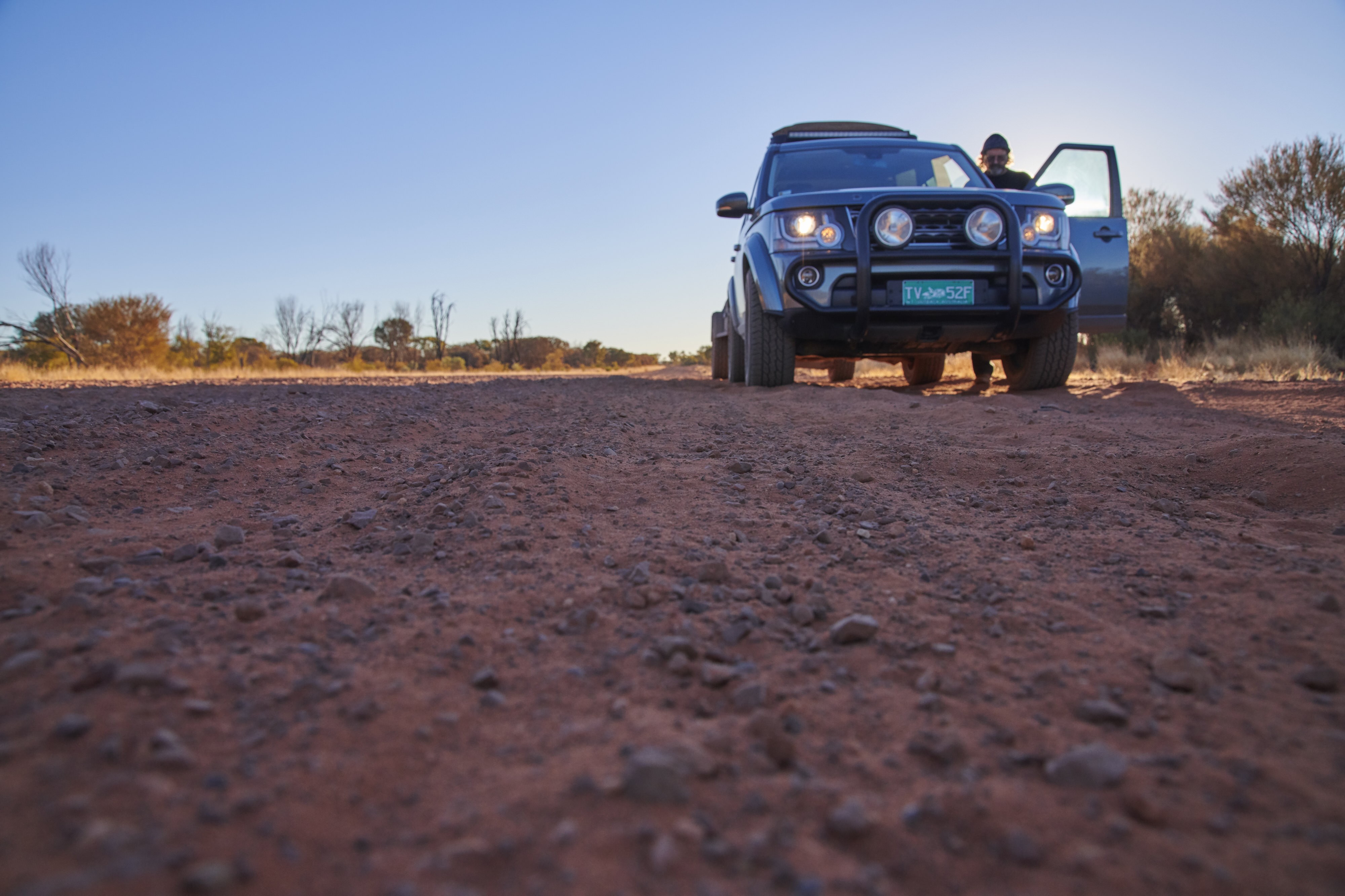 Ein Mann steht neben seiner Autotür auf der roten Outback-Piste in Australien