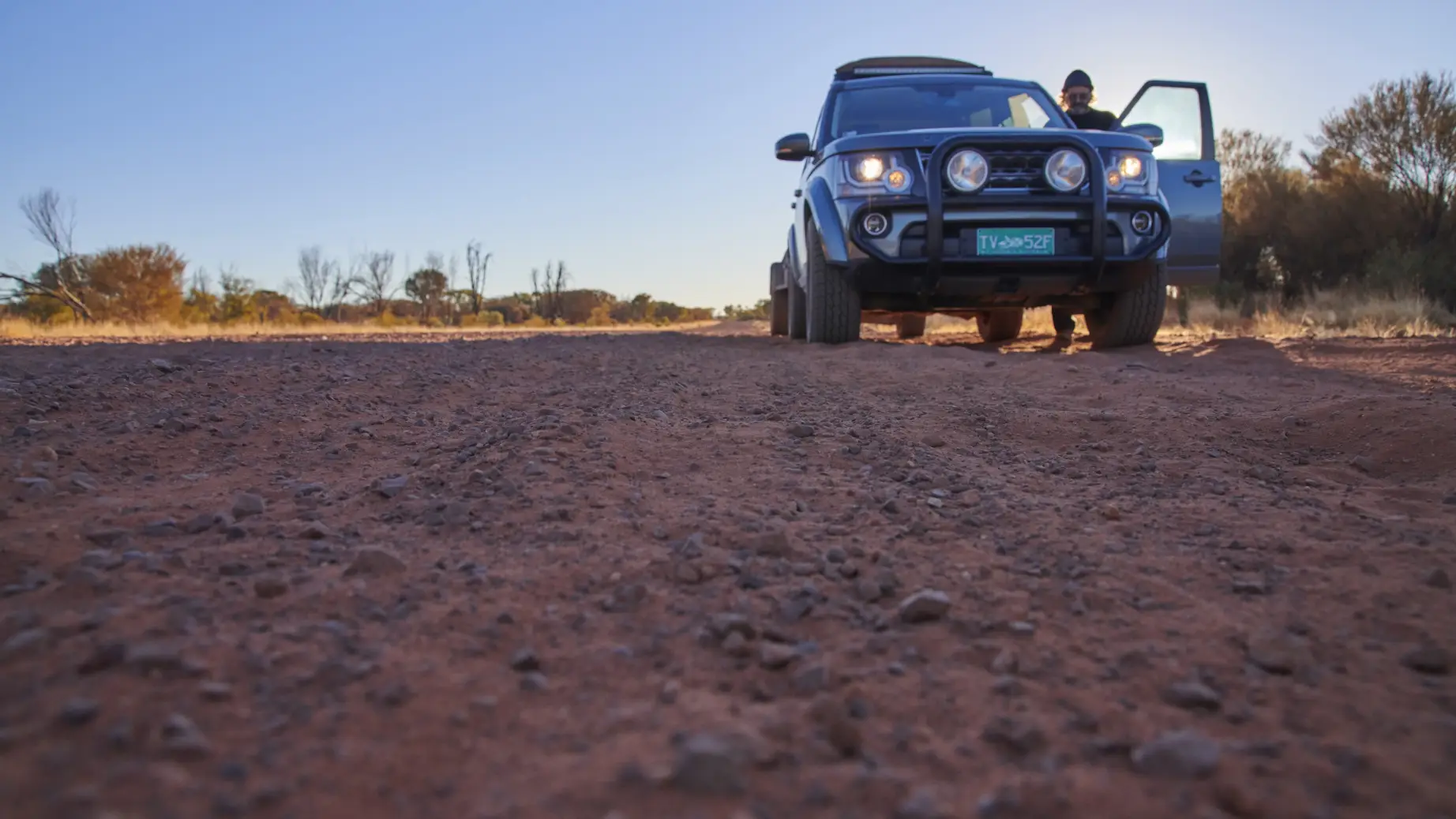 Ein Mann steht neben seiner Autotür auf der roten Outback-Piste in Australien