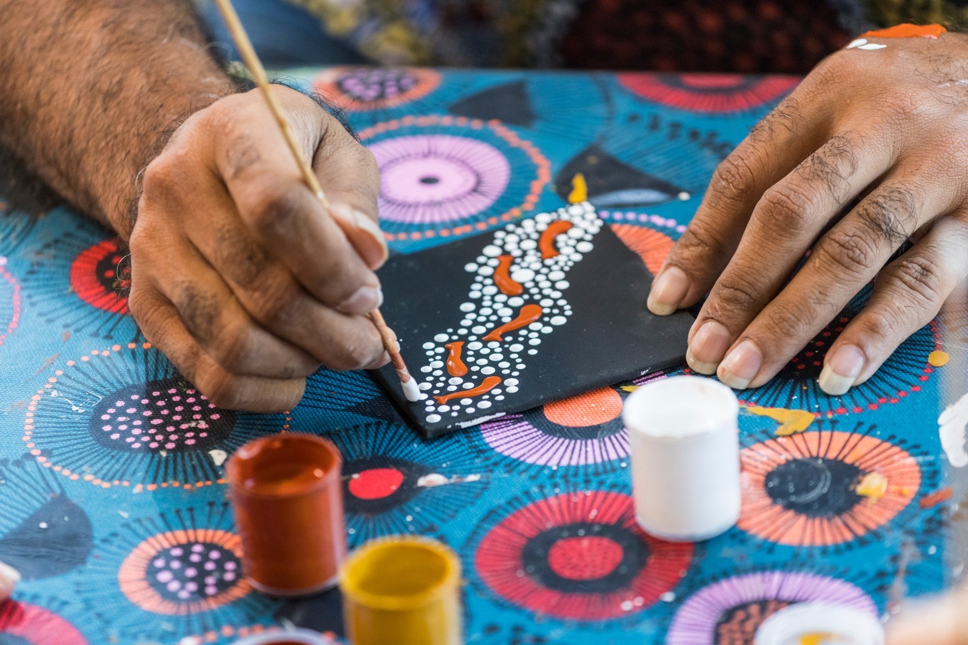 Jemandes Hände malen Aborigine-Kunst
