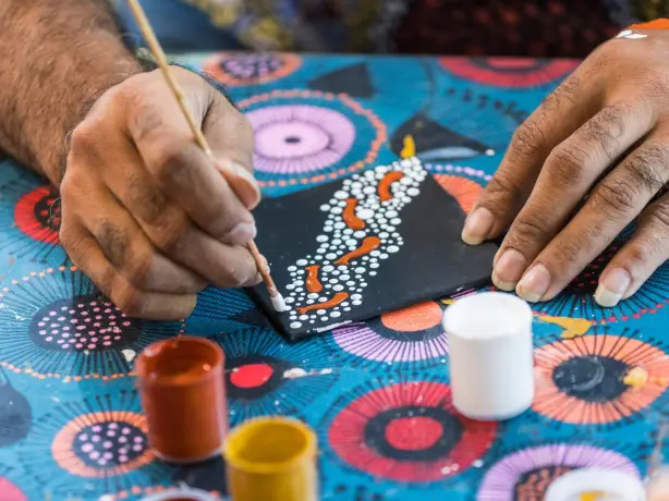 Jemandes Hände malen Aborigine-Kunst