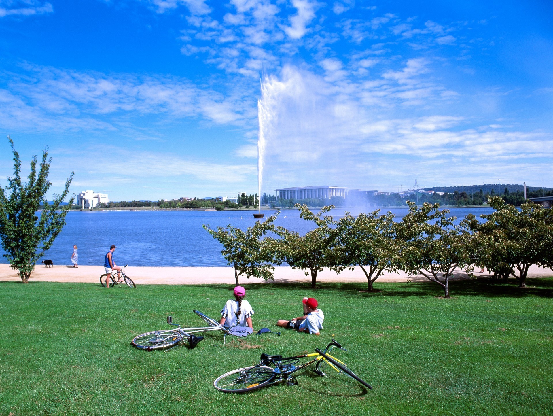 Australia, ACT – Friends sit in a park beside Lake Burley Griffin