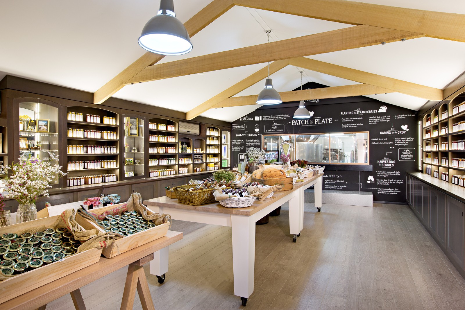 Hofladen mit Regalen mit Eingemachtem, Holztischen mit lokalen Produkten und einer Kreidetafel hinter dem Tresen.