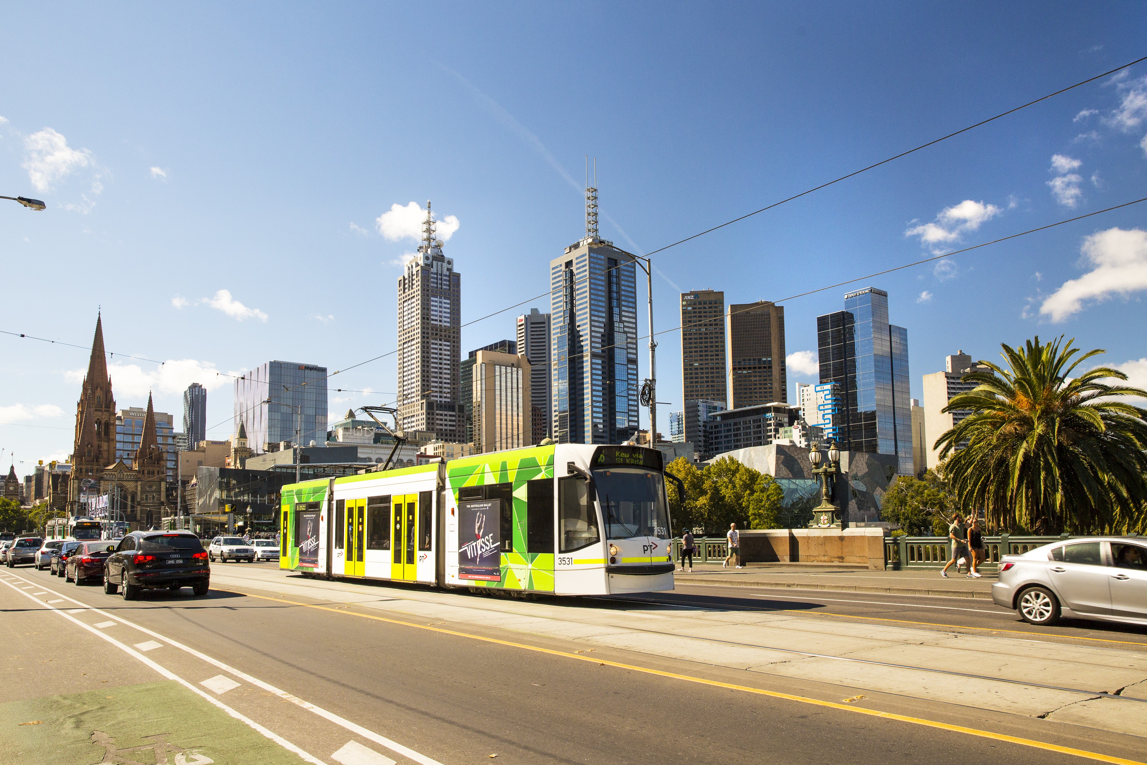 Eine Straßenbahn in Melbourne mit der Skyline der Stadt im Hintergrund