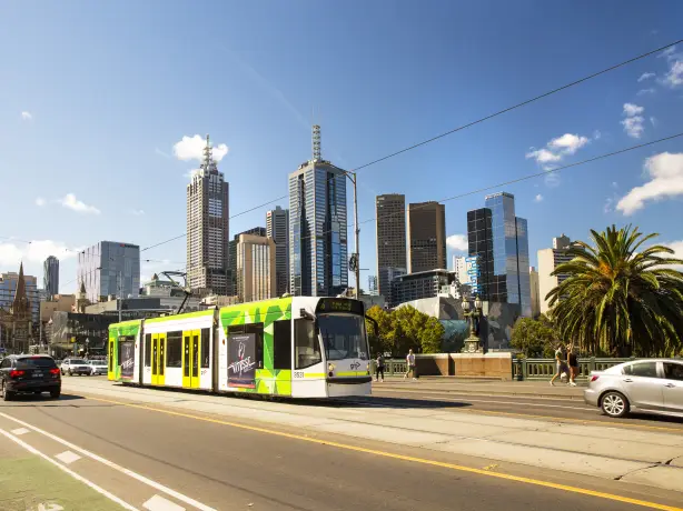 Eine Straßenbahn in Melbourne mit der Skyline der Stadt im Hintergrund