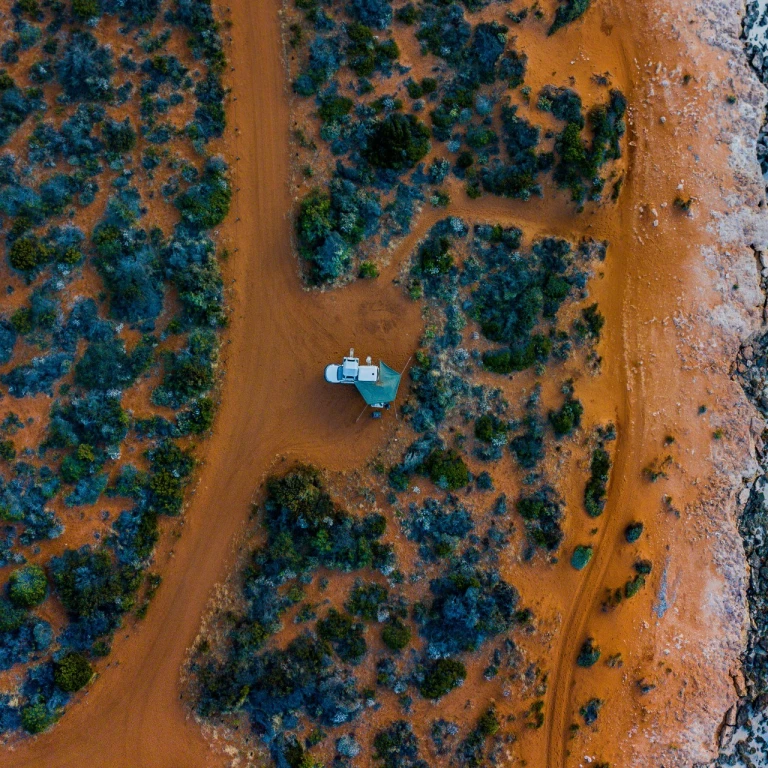 Vogelperspektive auf Camper, der auf rotem Sand an der Küste steht