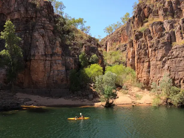 People paddle a yellow kayak on the Katherine River in Nitmiluk National Park, Australia