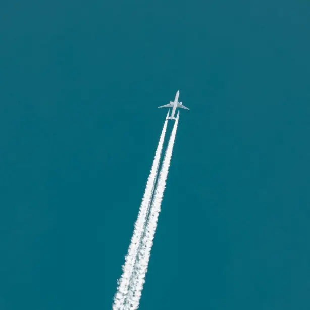 Plane flying through the sky with vapour trails