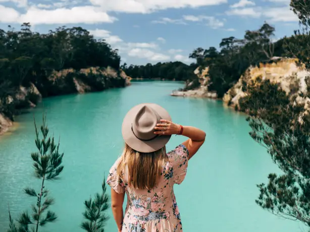 Frau mit Hut steht vor blauem See in Tasmanien