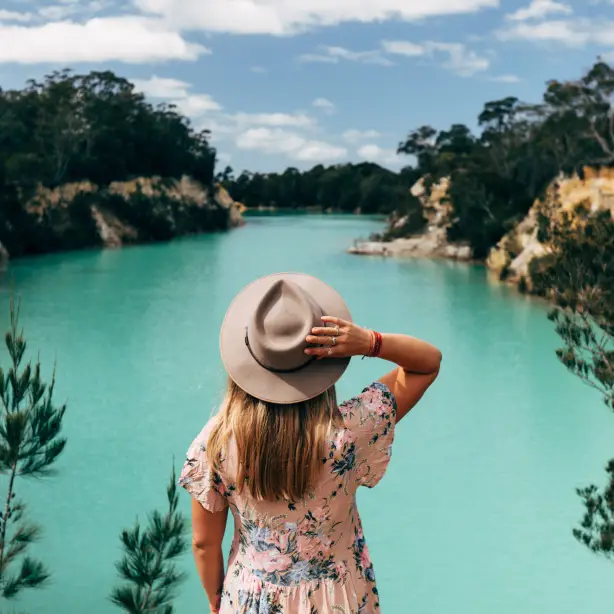 Frau mit Hut steht vor blauem See in Tasmanien