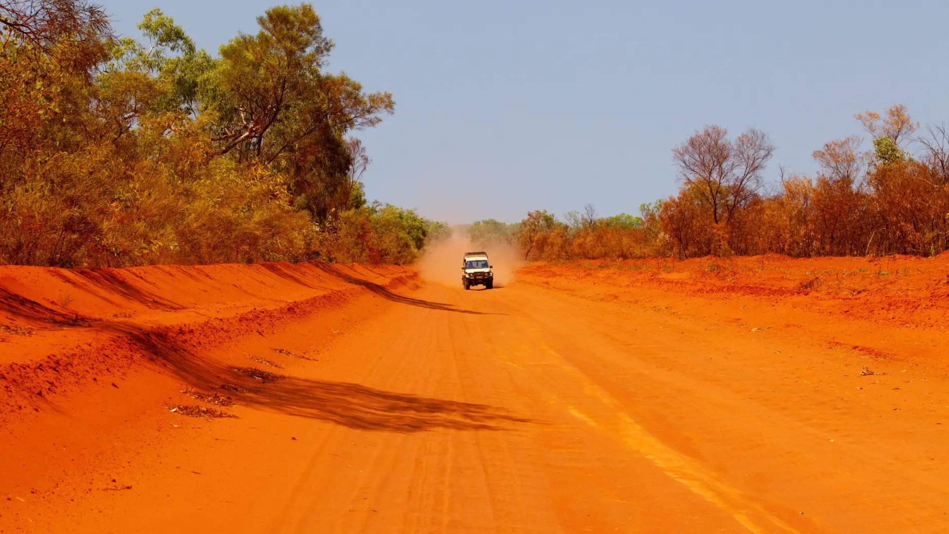 Ein Auto fährt auf einer roten Schotterstraße in Alice Springs, Northern Territory, Australien.