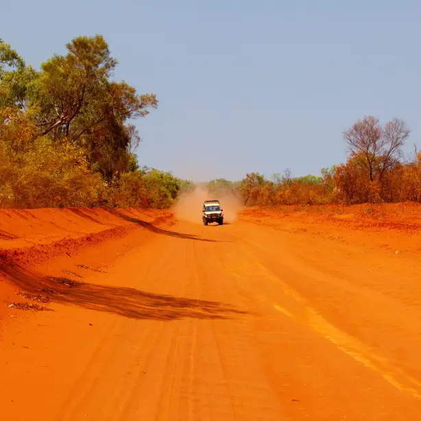 Ein Auto fährt auf einer roten Schotterstraße in Alice Springs, Northern Territory, Australien.