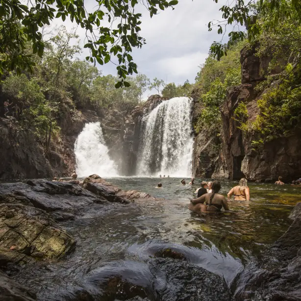 Mensen zwemmen in een rotspoel onder een waterval in Litchfield National Park, Australië