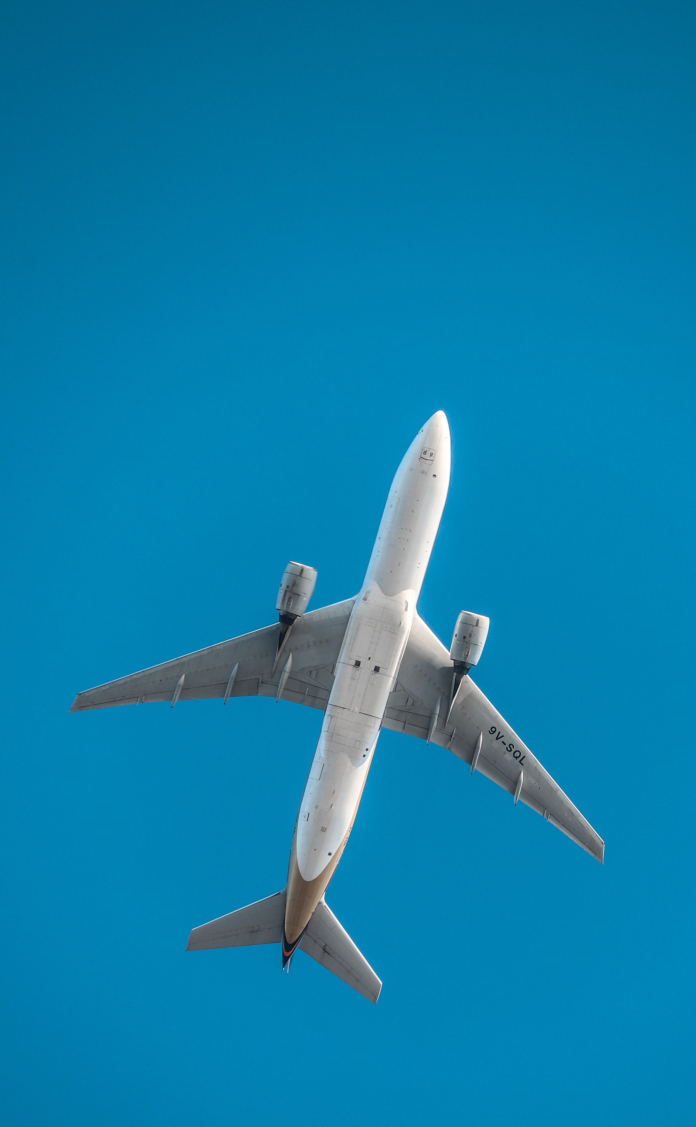 Unterseite eines fliegenden Flugzeugs, blauer Himmel im Hintergrund