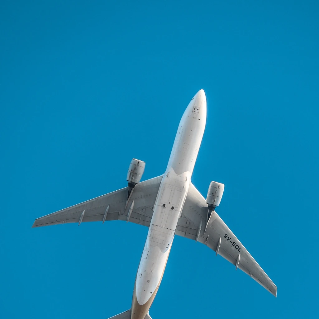 Unterseite eines fliegenden Flugzeugs, blauer Himmel im Hintergrund