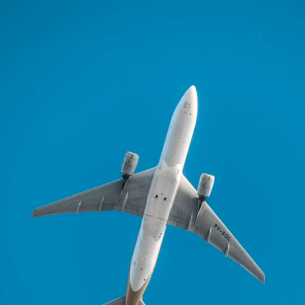 Underside of a plane flying, blue sky in the background